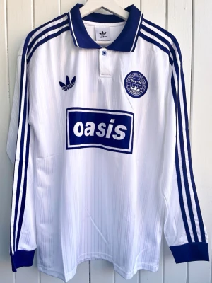 Oasis - Turné 25 - Långärmad fotbollströja  - Säljer en vit långärmad Oasis-supportertröja för bandets turné under 2025. Tröjan är en reprint i nyskick. Aldrig använd. ”25” på ryggen.      Storlek: Large    #Kent #Cd #Vinyl #England #fashion #sport #fashion #pop #rock #music #football