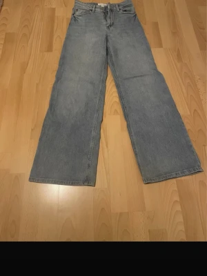 Blå raka jeans med loose fit - Säljer ett par klassiska blå jeans med rak och loose passform. Jeansen har fem fickor och stängs med dragkedja och knapp. Perfekta för en avslappnad och trendig stil.