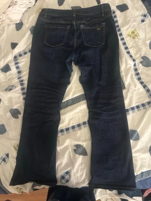 Mörkblå jeans från IVY, bootcut - Snygga mörkblå jeans från IVY i klassisk bootcut-modell. Jeansen har fem fickor, gylf med dragkedja och knapp samt kontrastsömmar. Perfekta för dig som gillar en tidlös och stilren look.