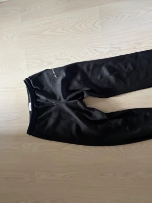 Svarta mjukisbyxor från Les Deux - Säljer ett par svarta mjukisbyxor från Les Deux med dragsko i midjan och broderad logga på vänster sida. Byxorna har raka ben, sidofickor och är gjorda i ett mjukt och bekvämt material som passar perfekt för chill dagar.