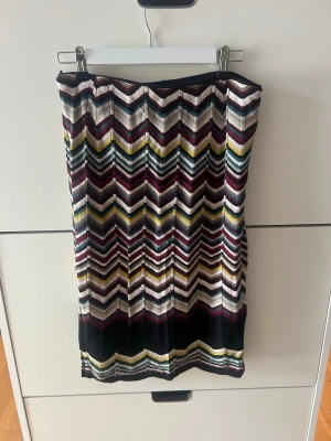 Mönstrad långkjol från Missoni x Lindex - Säljer en snygg långkjol från Missoni x Lindex med färgglatt sicksackmönster i vinrött, svart, vitt, gult och grönt. Kjolen har en rak passform och är tillverkad i ett mjukt material som känns bekvämt mot huden. Perfekt för dig som vill sticka ut med stil! Storlek 38