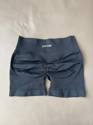 Svarta seamless cykelshorts DFYNE - Svarta seamless cykelshorts från DFYNE med hög midja och ribbad linning. Shortsen har scrunch-detalj bak och är tillverkade i ett stretchigt material som passar perfekt för träning och gym. Snygg och sportig design med logga framtill.