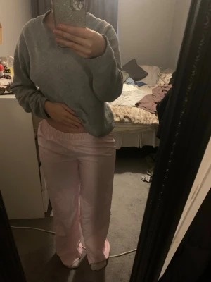 Rosa- och vitrandiga pyjamasbyxor - Säljer ett par pyjamasbyxor i mjukt material med rosa och vita tunna ränder. Byxorna har resår i midjan för extra komfort och en avslappnad passform. Perfekta för mysiga kvällar hemma. Helt oanvända🌸