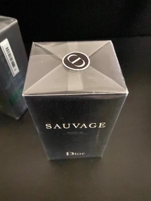 Dior Sauvage Parfum - Dior Sauvage Parfum är en lyxig herrdoft i en elegant, mörkblå rektangulär flaska med silverdetaljer. Förpackningen har en stilren design med tydlig Dior-logga och texten 'Sauvage' i vitt. Perfekt för dig som gillar exklusiva och moderna parfymer.
