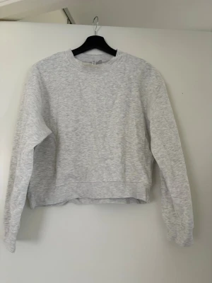 Ljusgrå sweatshirt från H&M BASIC - En enkel och stilren ljusgrå sweatshirt från H&M BASIC. Tröjan har rund halsringning, långa ärmar och är tillverkad i mjukt sweatshirtmaterial. Perfekt för en avslappnad och casual look. Lite smink på men går nog tvätta bort 