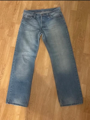 Ljusblå raka jeans - Säljer ett par ljusblå jeans med rak passform och klassisk femficksdesign. Jeansen har diskreta slitningar och ljusa partier framtill och baktill för en avslappnad look. Materialet är denim i bomull. Perfekta för en chill och stilren outfit….. Obs: igensydda slitngar men håller väldigt bra!!! Nypris: 2700 kr och modellen säljs inte längre!!!