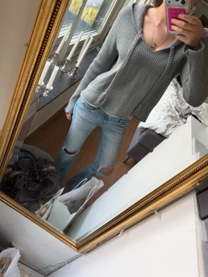 Grå stickad hoodie med snören💗 - Säljer en grå stickad hoodie med långa ärmar och huva. Tröjan har ribbstickat parti upptill och dekorativa snören med tofsar framtill. Jätte fina detaljer! Perfekt för en avslappnad och trendig look. Materialet är mjukt och bekvämt, passar till vad som helst!