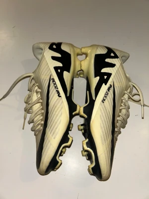 Nike Zoom fotbollsskor beige/svart - Snygga fotbollsskor från Nike med Zoom-teknologi. Skorna är beige med svarta detaljer och har en modern, strömlinjeformad design. Ovandelen är i syntetmaterial och sulan har fasta dobbar för spel på gräs. Perfekta för dig som vill ha stil och prestanda på planen. Använd fåtal gånger pågrund av fel storlek