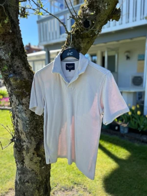 Beige pike i frotté - Beige pike i mjuk frotté med klassisk krage och korta ärmar. Perfekt för en avslappnad och stilren look. Enkel design utan tryck eller mönster, passar till det mesta.