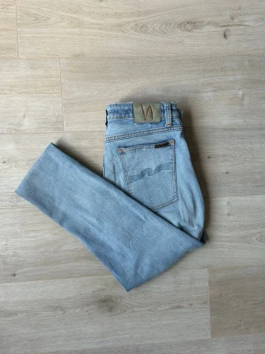 Ljusblåa Nudie Skinny Lin Jeans W33 L32 - Mycket fina Nudie Jeans i blå färg. Jeansen är i mycket bra skick och sparsamt använda. |  Äkta som allt annat jag säljer! ✅ |  Storlek: W33 L32 | Skick: Mycket Bra Skick - tyvärr en väldigt liten slitning | Färg: Blå | Märke: Nudie | Modell: Jeans |   Hör gärna av dig vid frågor så svarar jag så fort jag kan! 😁 |  (SKU - 117)