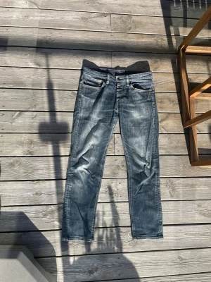 Levis 511 exklusive **svart tagg** - Säljer ett par klassiska blå Levi's jeans med snygga slitningar och tvättad look. Jeansen har fem fickor, raka ben och en röd Levi's-tag på bakfickan. Tillverkade i denim med en cool vintagekänsla. Perfekta för en avslappnad stil.