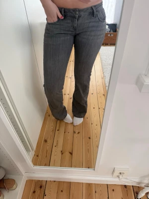Grå flared jeans med låg midja - Snygga grå jeans med flared ben och låg midja.  Materialet är denim och de har en patch bak i midjan. Jag är 173 för referens! Har ett bar till jeans i min profil. Brukar ha M dessa sitter nog bättre för någon med S/M🤗 köpte för 800 så 50%! Kan förhandla såklart