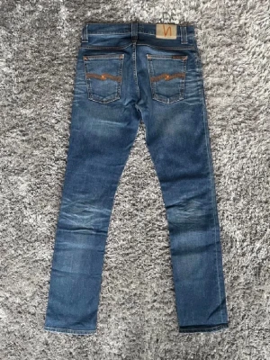 Blå jeans från Nudie Jeans - Säljer dessa feta jeansen från Nudie Jeans. Storlek 29/32. Jeansen har en fet fade och passar till massor av sköna outfits. Skick 8/10. Hör gärna av er om ni har några funderingar!