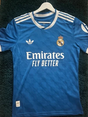 Real madrid 25/26 bortatröja Authentic - Snygg blå Real Madrid matchtröja från Adidas med vita detaljer och klubbmärke på bröstet. Tröjan är autentisk och har inte varit använd någon gång och är nyligen köpt och säljer den nu på grund av att passformen var lite för tajt
