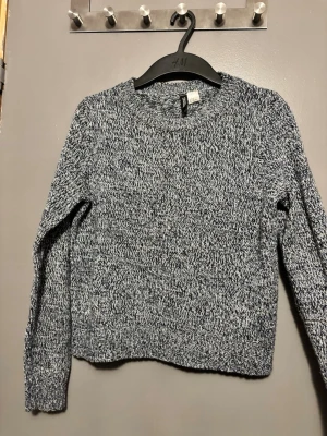 Blå stickad tröja H&M - En blå stickad tröja från H&M med rund halsringning och långa ärmar. Tröjan har en grovstickad struktur. 