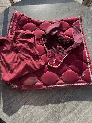 Supersnyggt vinrött ps sett - Super snyggt sett från ps of Sweden Endast använda vid 2 tävlingstillfällen, (lite ytligt smuts där sadelgjorden suttit) Storlek full i både huva och schabrak  Storlek L i tröjan men passar både M och L Kan sälja separat men helst tillsammans☺️