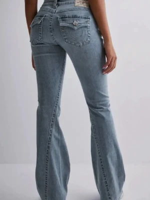 Blå bootcut jeans från True Religion - Säljer ett par ljusblå bootcut jeans från True Religion med klassiska kontrastsömmar och fickor med lock bak. Perfekta för dig som gillar retrovibbar och snygg siluett. Skriv för egna bilder. ( priset kan diskuteras💕)