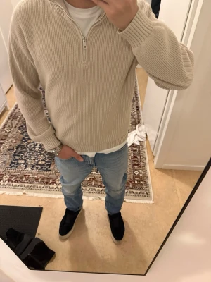 Beige stickad half zip-tröja Kappahl - Snygg beige stickad tröja från Kappahl med half zip-dragkedja och hög krage. Tröjan har ribbade muddar och är långärmad. 