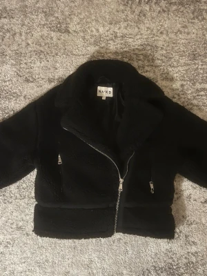 Svart teddyjacka från NA-KD - Mysig svart teddyjacka från NA-KD i storlek 36!med bred krage och två snedställda dragkedjefickor framtill. Skriv vid frågor eller fler bilder!🩷