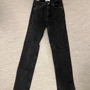 Svarta raka jeans från Gina Tricot - Snygga svarta jeans från Gina Tricot med hög midja och raka ben. Klassisk femficksmodell med bälteshällor och läderpatch bak i midjan. Perfekta till en trendig vardagslook.