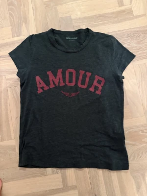 Svart t-shirt med röd text från Zadig & Voltaire  - Cool svart t-shirt från Zadig med röd texten 'AMOUR' på bröstet. Klassisk rund halsringning och korta ärmar. 