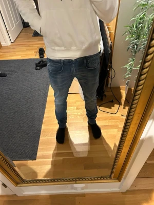 Blå slim fit jeans med slitningar - Snygga blå slim fit jeans med lätt slitna detaljer och klassisk femficksdesign. Jeansen har normal midja och smal passform hela vägen ner. Perfekta för en avslappnad och trendig look. Mycket bra skick. Storlek 31/32