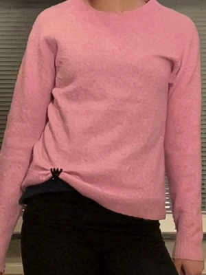 Rosa stickad tröja med rund hals - Mysig rosa stickad tröja med rund halsringning och långa ärmar. Tröjan har ribbstickade muddar vid ärmslut och nederkant. Perfekt för kyliga dagar och enkel att matcha med olika outfits.