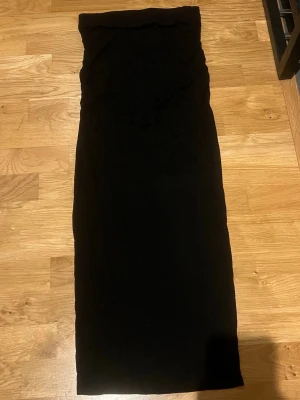 Svart långkjol från Gina tricot  - En svart långkjol med rak passform och minimalistisk look. Kjolen är utan synliga detaljer och passar perfekt till många olika stilar. Materialet känns mjukt och följsamt, vilket gör den bekväm att bära hela dagen.