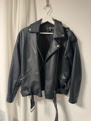 Svart skinnjacka - Snygg svart oversized skinnjacka från  Missguided med bälte i midjan. Som ny och perfekt nu till våren!