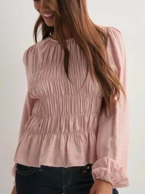 Ljusrosa blus med smock - Ljusrosa blus med smockade partier och volang nedtill. Blusen har rund halsringning och långa, puffiga ärmar med resår vid ärmslut. Materialet ser ut att vara lätt och mjukt, perfekt för en trendig look. Ny pris 300. Säljer då den är lite för stor. Nästan aldrig använt. Pris kan diskuteras 