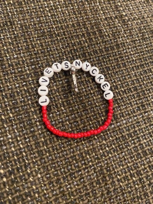 Armband med textpärlor och röda pärlor - Unikt armband med vita bokstavspärlor som stavar 'LIVETS NYCKEL' och små röda pärlor. Armbandet har även en liten metallberlock i form av en nyckel. Perfekt accessoar för dig som gillar personliga smycken.