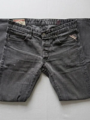 Svarta Replay jeans - Snygga svarta jeans från Replay. En lätt tvättad look med diskreta slitningar. De har passformen slim fit och är i strlk 32/32. I nyskick!