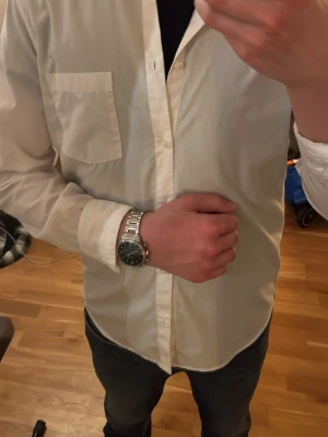 Vit klassisk skjorta med bröstficka - Säljer en stilren vit skjorta med lång ärm och klassisk krage. Nytt skick men säljer billigt på grund av ingen användning. Skjortan har en bröstficka och knäppning framtill. Perfekt att matcha med jeans eller chinos för en clean look.