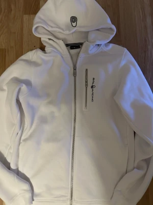 Sail racing zip up - Säljer min vita zip up från sail racing. Den enda gången jag haft på mig den var när jag provade den, jag säljer den då jag behöver pengar. Storlek 176, nypris är på 899