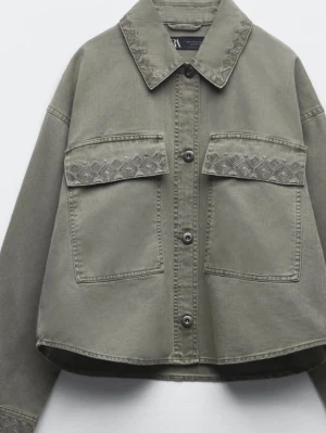  jeansjacka från Zara i XS -  jeansjacka från Zara med boxy passform och broderade detaljer på bröstfickorna,krage och nere på ärmarna. Jackan har stora fickor framtill, knäppning med  knappar och klassisk krage. 