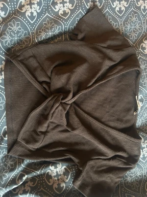 Svart ribbad omlottopp - Snygg svart ribbad omlottopp med korta ärmar och knyt framtill. Perfekt för att skapa en trendig och avslappnad look. Toppens material är mjukt och stretchigt, vilket gör den bekväm att bära hela dagen. Den är i storlek s, skriv för mer info