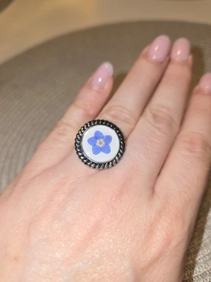 Ring med en föegätmigej - Epoxi ring med en förgätmigej inuti. Materiall - rostfritt stål. 