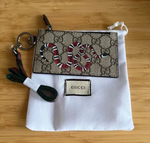  plånbok med orm och GG-mönster - Plånbok med GG möster som man kan hänga runt halsen med rött och grönt mönster 