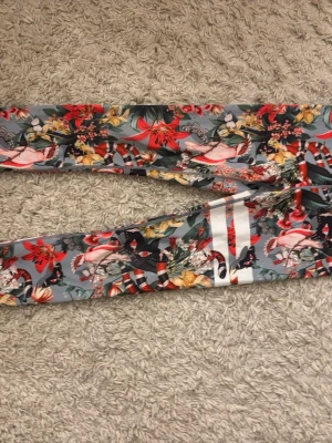 Leggings från Stronger - Snygga leggings från Stronger med färgglatt blommönster. Tight passform och stretchigt material. I bra skick och har används fåtal gånger.