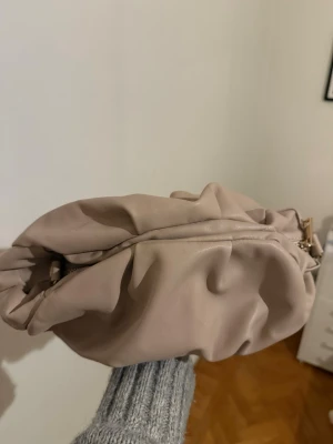 Beige puffig clutchväska i fejkläder - Trendig beige clutchväska i mjukt fejkläder från asos, använd en gång