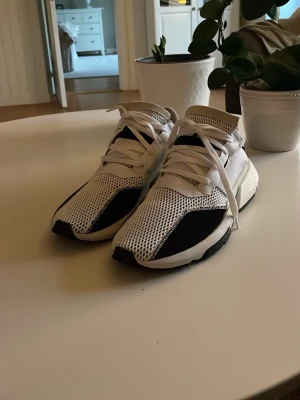 Vita och svarta Adidas sneakers - Snygga Adidas sneakers i vitt och svart med mesh-ovandel och chunky sula. Skorna har en modern design med vita snören och svarta detaljer på tå och sula. Perfekta för dig som gillar streetwear och sportig stil.