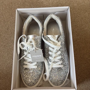 Glittriga silvriga sneakers från Touch-It/Tamaris - Säljer dessa snygga coola silver glittriga sneakers då jag tyvärr aldrig fått användning av de. Skorna är i perfekt skick och bara provade😍Perfekt för fest eller en vardag för att piffa upp en outfit✨🪩🥰 hör av dig ifall du är intresserad eller har andra frågor 🫶🏽