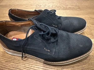 Svarta loafers från Zeus - Snygga blåa loafers från Zeus med texturerad ovandel och klassisk snörning. Skorna har en kontrasterande vit sula och bruna detaljer på insidan. Perfekta för dig som gillar stilrena och tidlösa skor med en modern touch.