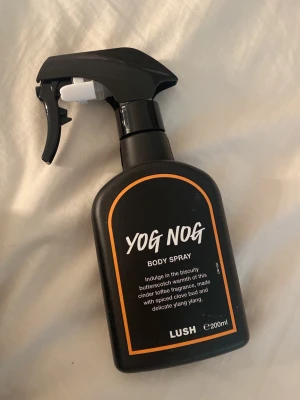 Yog Nog Body Spray från Lush - Yog Nog Body Spray från Lush med en varm doft av butterscotch, cinder toffee, kryddnejlika och ylang ylang. Rymmer 200 ml och är vegansk. Oanvänd. 