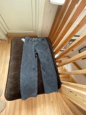 Svarta raka jeans från Weekday - Säljer ett par svarta jeans från Weekday med klassisk femficksmodell och hög midja. Jeansen har en enkel design utan slitningar och är tillverkade i kraftig denim. Perfekta för dig som gillar en clean och tidlös look. Aldrig använd för jag har köpt fel storlek