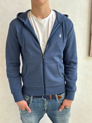 Blå zip hoodie från Ralph Lauren - Säljer nu denna zip hoodien från ralph lauren. Skicket är 10/10. Modellen på bilden är 184cm och väger 80kg. Bara att höra av sig vid minsta fundering! 