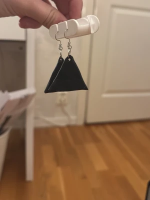 Svarta trekantsörhängen - Unika örhängen i svart med trekantig form och silverfärgade krokar. Perfekta för dig som gillar grafiska och minimalistiska accessoarer. Lätta att bära och ger en cool touch till din stil.