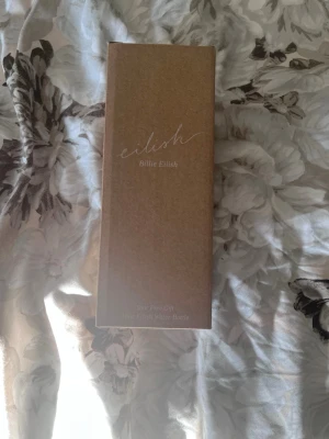 Eilish Billie Eilish vattenflaska - Säljer en exklusiv Eilish Billie Eilish vattenflaska i glas, levereras i originalkartong. Flaskan har ett skyddande silikonhölje och är designad med Billie Eilishs signatur. Perfekt för dig som gillar snygga och praktiska accessoarer.