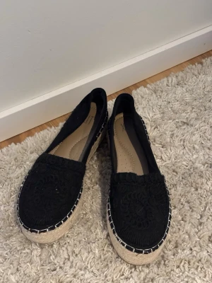 Loafers  - Säljer ett par svarta sommarskor med snyggt virkade detaljer på ovandelen och en naturfärgad flätad sula. Skorna har rund tå och dekorativa sömmar runt sulan. Perfekta för en avslappnad och trendig look.🌸🎀🩷☀️