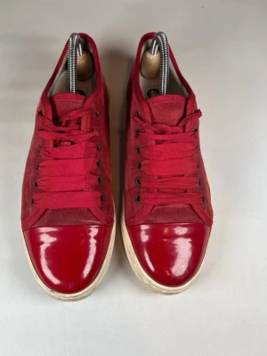 Röda låga sneakers i mocka och lack - Snygga och stilrena Lanvin DBB1 i röd mocka med lackad tå. Klassisk low-top modell med vit sula – passar till allt. Äkta!   Bra skick (se bilder) Bekväma och exklusiva Nypris ca 5 000+ kr Stl 40  Säljes till bra pris 🔥